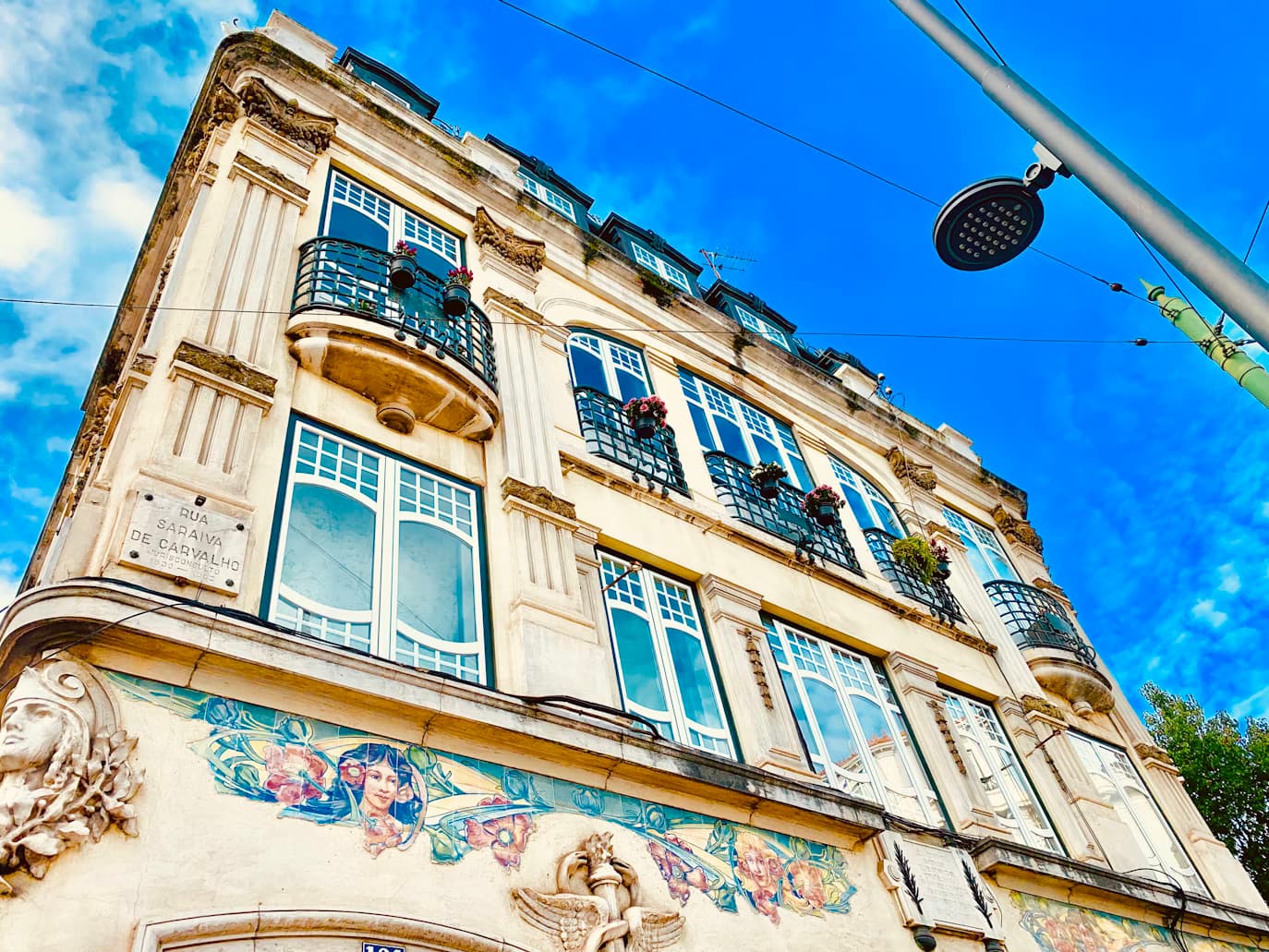 Campo de Ourique: um prédio alto com muitas janelas sob um céu azul.